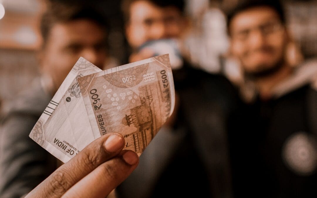 Person holding money (in Indian rupees) with 3 well dressed people in the backgroun side by side ddressed smartly, with a celebration vibe