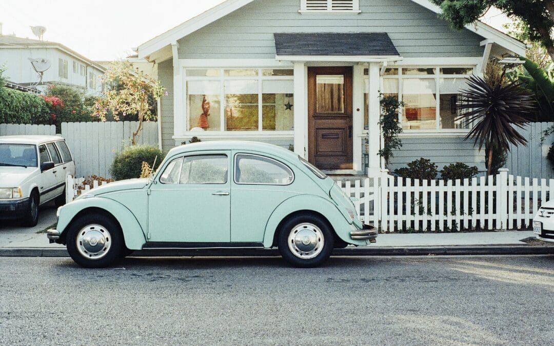 Vintage picture showing a house and a light green beetle Volkswagen car