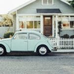 Vintage picture showing a house and a light green beetle Volkswagen car